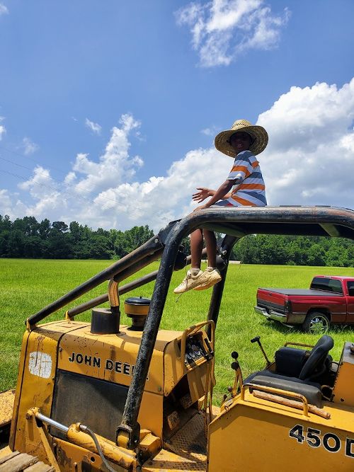 Kai Lee hangs out on a John Deere, overlooking the fields as the summer harvest begins.